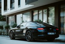 Driving in Elegance: the Growth of the Luxury Car Rental Market in Italy Bentley Continental GT W12 3 (third generation) is parked near newly constructed appartment building. Side-back view, vintage lens.