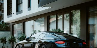 Driving in Elegance: the Growth of the Luxury Car Rental Market in Italy Bentley Continental GT W12 3 (third generation) is parked near newly constructed appartment building. Side-back view, vintage lens.