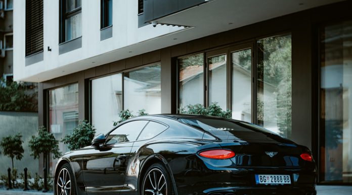 Driving in Elegance: the Growth of the Luxury Car Rental Market in Italy Bentley Continental GT W12 3 (third generation) is parked near newly constructed appartment building. Side-back view, vintage lens.