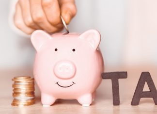 Money beside the piggy bank and tax word