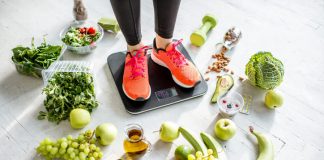 woman weighing on the scales with healthy foods around