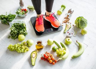 woman weighing on the scales with healthy foods around