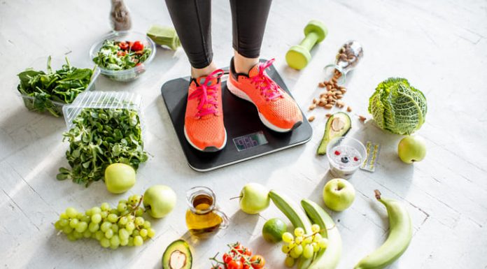 woman weighing on the scales with healthy foods around