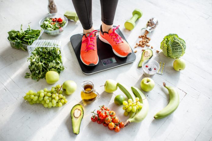 iStock-1129673037 (1) woman weighing on the scales with healthy foods around