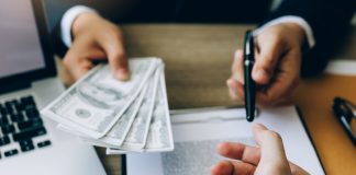 How Can I Borrow Money Urgently? Partner has made a fraud in the contract of sale and being handed a cash and pen to the businessman signing the contract corruption bribery concept.