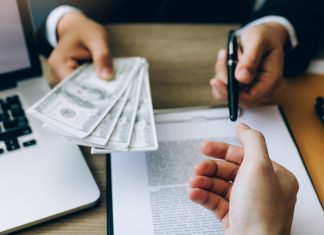 Partner has made a fraud in the contract of sale and being handed a cash and pen to the businessman signing the contract corruption bribery concept.