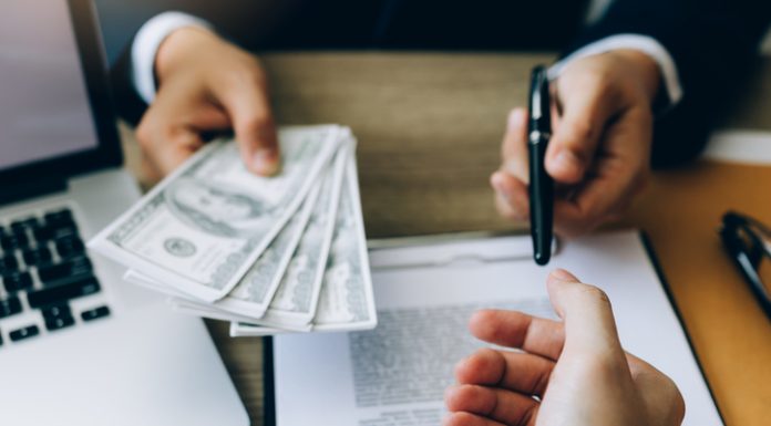 How Can I Borrow Money Urgently? Partner has made a fraud in the contract of sale and being handed a cash and pen to the businessman signing the contract corruption bribery concept.