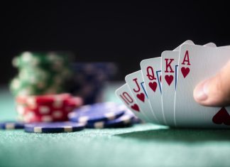 Playing poker in a casino holding winning royal flush hand of cards