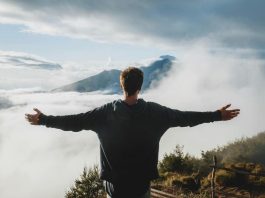 Man with arms outstretched admiring view from mountain cliff