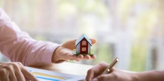 Estate agent pointing finger on document showing total cost. Signing a paper document for buying house.