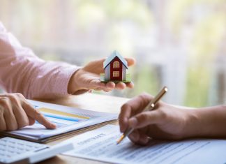 Estate agent pointing finger on document showing total cost. Signing a paper document for buying house.
