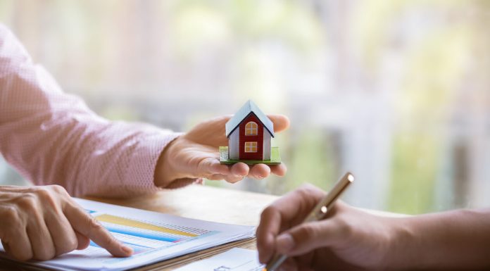 Estate agent pointing finger on document showing total cost. Signing a paper document for buying house.