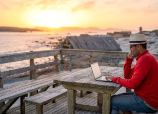 A man working on a laptop outdoors at the beach. A man working on a laptop outdoors at the beach.