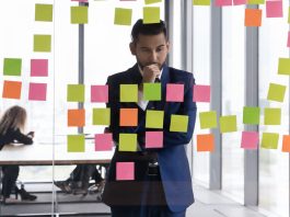 Young pensive Indian businessman in suit stand near glass wal