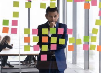 Enhancing Decision-Making Skills in Employees: Strategies for Organizational Success Young pensive Indian businessman in suit stand near glass wal