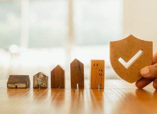 Wooden house model and real estate insurance ideas, and small shield icon.