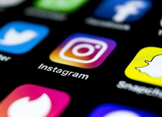 Apple iPhone X on office desk with icons of social media network instagram application on screen. Social network. Starting social media app.