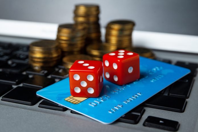 Gambling online. Playing dices and money with credit card on laptop keyboard. Gaming addiction Online gambling