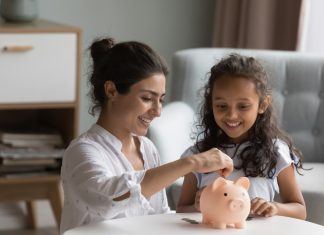 mother and kid dropping cash into piggy bank