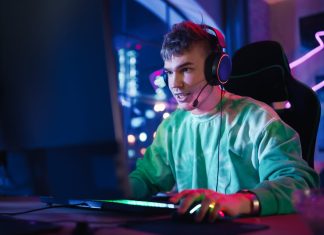 Gaming at Home: Portrait of a Gamer Wearing Headphones and Playing Online Game on Personal Compute