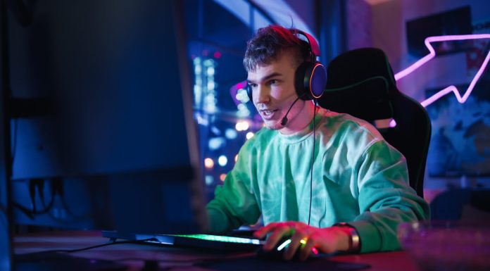 Gaming at Home: Portrait of a Gamer Wearing Headphones and Playing Online Game on Personal Compute