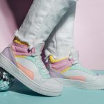 Close up photo of legs wearing retro style high-top multicolor sport sneakers shoes with disco ball on blue and pink background. Minimalism party, vintage retro style of 80s - 90s vibes.