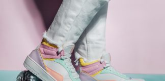 Close up photo of legs wearing retro style high-top multicolor sport sneakers shoes with disco ball on blue and pink background. Minimalism party, vintage retro style of 80s - 90s vibes.
