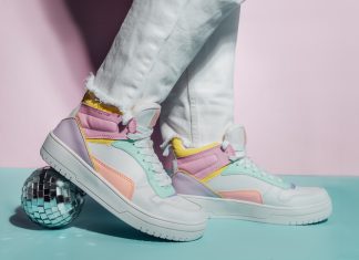 Close up photo of legs wearing retro style high-top multicolor sport sneakers shoes with disco ball on blue and pink background. Minimalism party, vintage retro style of 80s - 90s vibes.