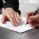 Manager showing client where she must to mark signature at dark table, closeup