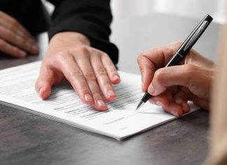 Manager showing client where she must to mark signature at dark table, closeup