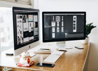 Two Imac's With Keyboard and Phones on Desk