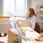 Man passing papers to colleague in office