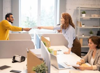 Man passing papers to colleague in office