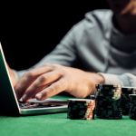How the History of Online Gambling in Saudi Arabia Unfolds: Challenges and Opportunities Man using laptop with casino chips