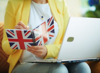 How Easy Is It To Study A Business Degree Within The UK? Female taking down notes in a UK flag notebook
