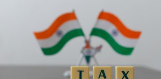Tax on pile of coins and blur Indian Flag