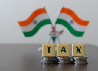 Tax on pile of coins and blur Indian Flag