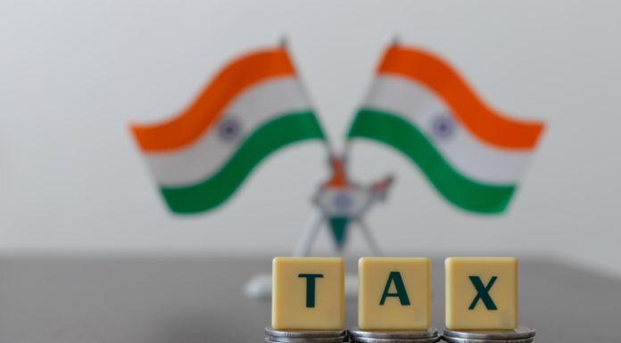 Tax on pile of coins and blur Indian Flag