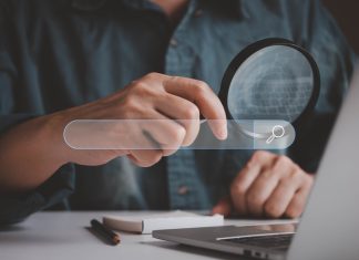 How Important Is Online Visibility When It Comes to Business Success? Man holding magnifying glass while using computer