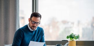 Busy elegant bearded adult company director, checking the company finances, at the office.