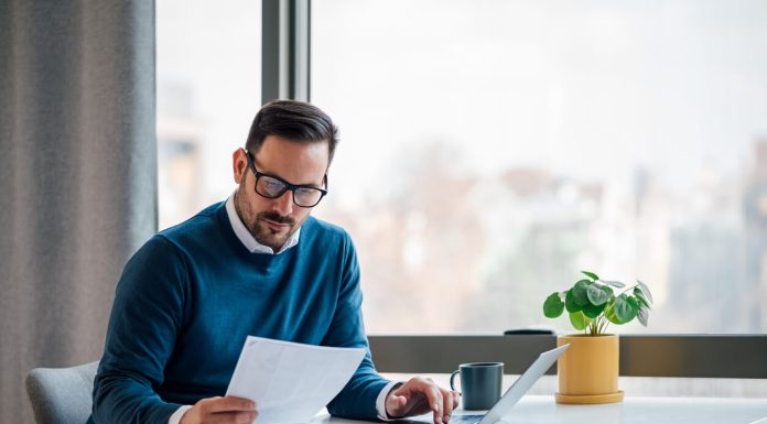 Busy elegant bearded adult company director, checking the company finances, at the office.