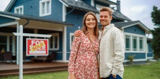 Couple standing behind their new home