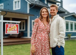 Couple standing behind their new home