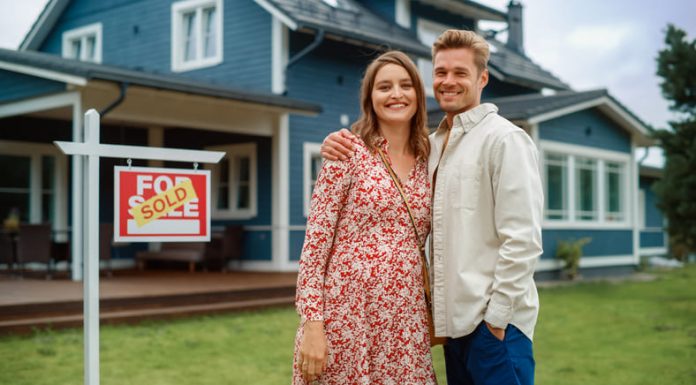 Couple standing behind their new home
