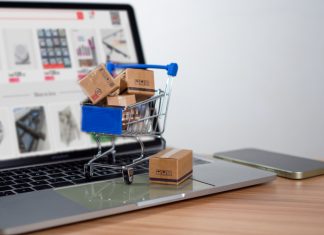 Shopping cart and product boxes placed on laptop computer for e-commerce