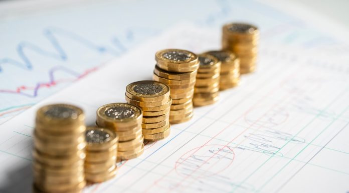 Stack of pound coins on financial graphs and figures balance sheet