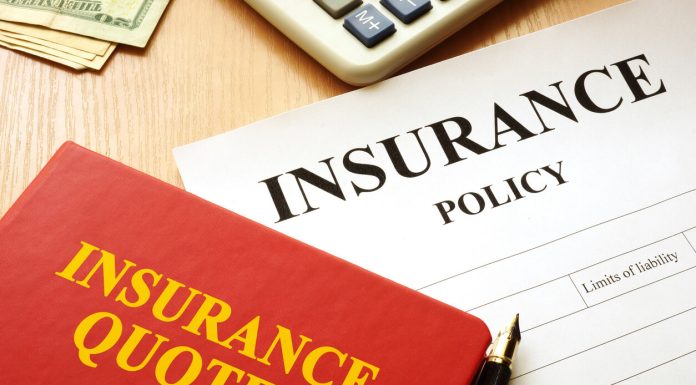 Insurance quotes book and policy on a desk.