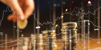 Double exposure. Hand holding golden coin of graph and rows with coins on wooden table. Finance and business concept.