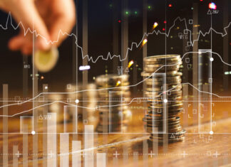Double exposure. Hand holding golden coin of graph and rows with coins on wooden table. Finance and business concept.
