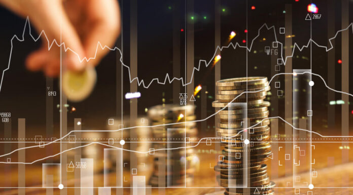 Double exposure. Hand holding golden coin of graph and rows with coins on wooden table. Finance and business concept.